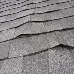 Buckled shingles on roof during spring